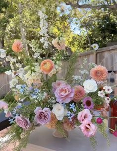 a vase filled with lots of flowers on top of a table next to a wooden fence