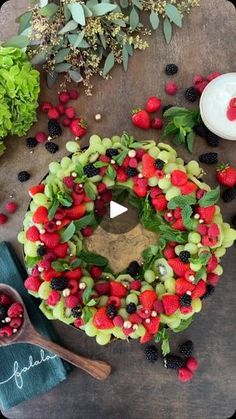 a wreath made out of fruit and berries on top of a wooden table next to other fruits