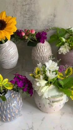 several vases filled with different types of flowers on a white counter top next to each other