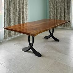 a wooden table sitting in front of a window with drapes on the windowsill