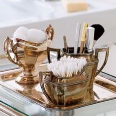 there is a gold cup with makeup brushes in it on the bathroom sink countertop