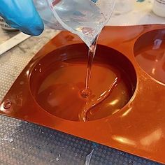 someone is pouring liquid into an orange tray