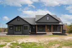 a large gray house sitting on top of a lush green field