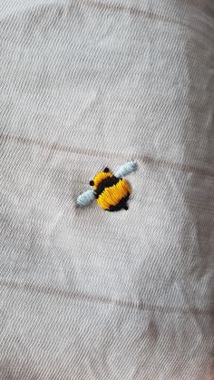 a small yellow and black bee sitting on top of a bed