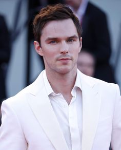 a close up of a person wearing a white suit and tie with one hand in his pocket