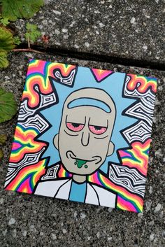 a painting of a man with pink eyes and blue hair is on the ground next to some plants