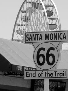 a sign that says santa monica and the end of the trail with a ferris wheel in the background