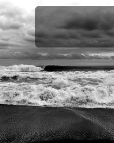 black and white photograph of waves crashing on the beach with dark clouds in the background