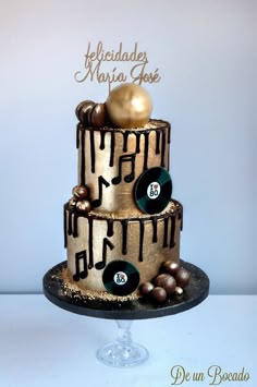 a three tiered cake decorated with gold and black music themed icing on top