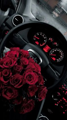 a bouquet of red roses sitting in the drivers seat of a car next to a steering wheel