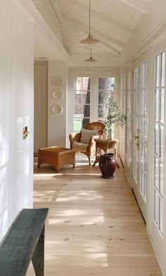 the sun shines through the windows onto an empty hallway with wicker furniture and potted plants