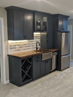 a kitchen with gray cabinets and stainless steel appliances in the center, along with a wine rack on the island