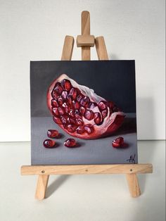 a painting of a pomegranate on an easel with pieces of fruit