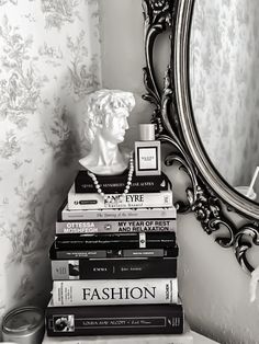 a stack of books sitting on top of a table next to a mirror