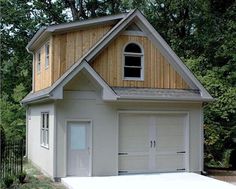 a white garage with a window and two doors on the front, surrounded by trees