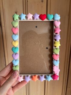 a person holding up a small frame with hearts and stars on it