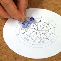 someone is doing something with blue markers on the paper that looks like a circular design