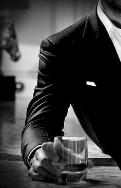 a man sitting at a table with a glass in front of him and his hand on the cup