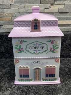 a pink and white coffee shop with windows on the roof is sitting on a granite countertop