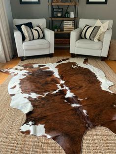 a living room with two chairs and a cowhide rug