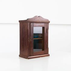 an old wooden cabinet with glass doors on the top and bottom shelf, in front of a white wall