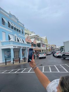 a woman holding up her cell phone to take a selfie in the middle of an empty street