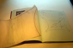 an open notebook with a pattern on it and a piece of paper next to it