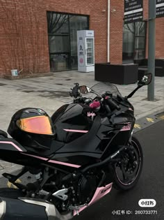 a pink and black motorcycle parked on the street in front of a brick building next to a sidewalk