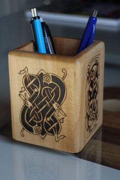 a wooden pen holder with two pens in it