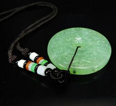 Green Carved Amulet Necklace, Carved Round Jade Jewelry, Carved Green Round Jewelry, Round Carved Jade Jewelry, Green Carved Round Jewelry, Carved Jade Jewelry For Good Luck, Traditional Jade Medallion Jewelry, Green Carved Round Pendant Jewelry, Flower Donut