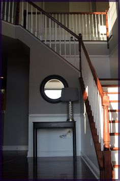 an empty room with stairs and a round mirror on the wall next to a table