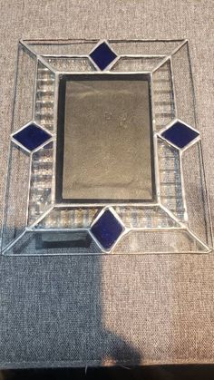 a glass table with blue and white tiles on it's sides, in the shape of a square