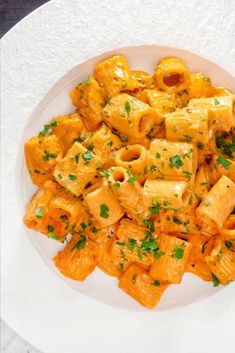 a white plate topped with pasta covered in sauce and garnished with parsley