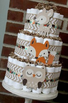 a three tiered cake with paper animals on it's top and two rolls of toilet paper in the bottom