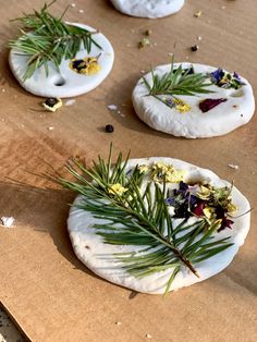 three small pizzas with herbs and flowers on them