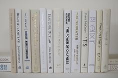 a row of books sitting on top of a white book shelf next to each other