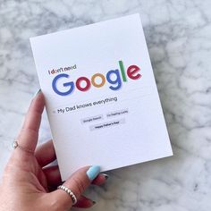 a woman holding up a google book on top of a marble countertop with the title i can't read google my dad wrote everything