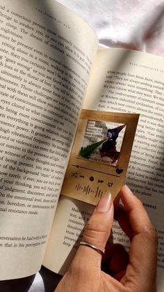 a person holding an open book with a bird on it's cover and the pages are folded in half