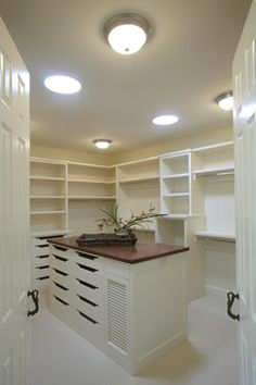 an empty room with lots of white cabinets and drawers on the wall, along with lights