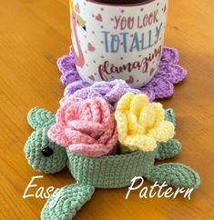 a crocheted turtle sitting next to a coffee cup