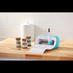 a cutting board with some jars on it and a pen in the holder next to it