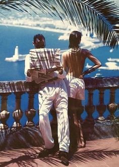 two people sitting on a bench looking out at the ocean with palm trees in the foreground