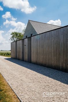 a wooden building with a metal fence on the side and gravel road leading to it