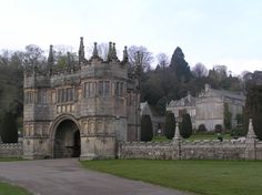 an old castle with stone walls and towers in the middle of a green park area