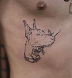 a dog tattoo on the side of a man's chest, with a chain around his neck