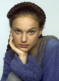 a beautiful young woman sitting down with her hand on her chin and looking at the camera