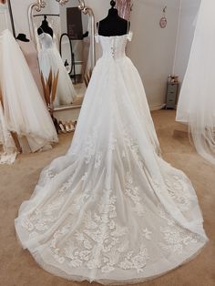 a white wedding dress on display in a bridal room with mannequins