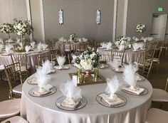 the tables are set with white flowers and silver plates