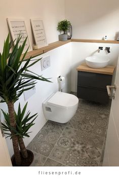 a white toilet sitting next to a plant in a bathroom