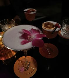 a table topped with glasses filled with different types of drinks and flowers on top of it